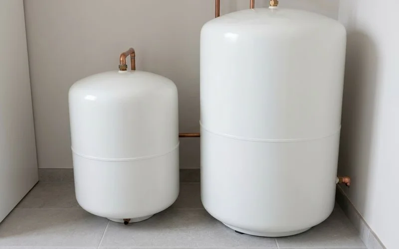 A small storage water heater tank next to a larger one for size comparison